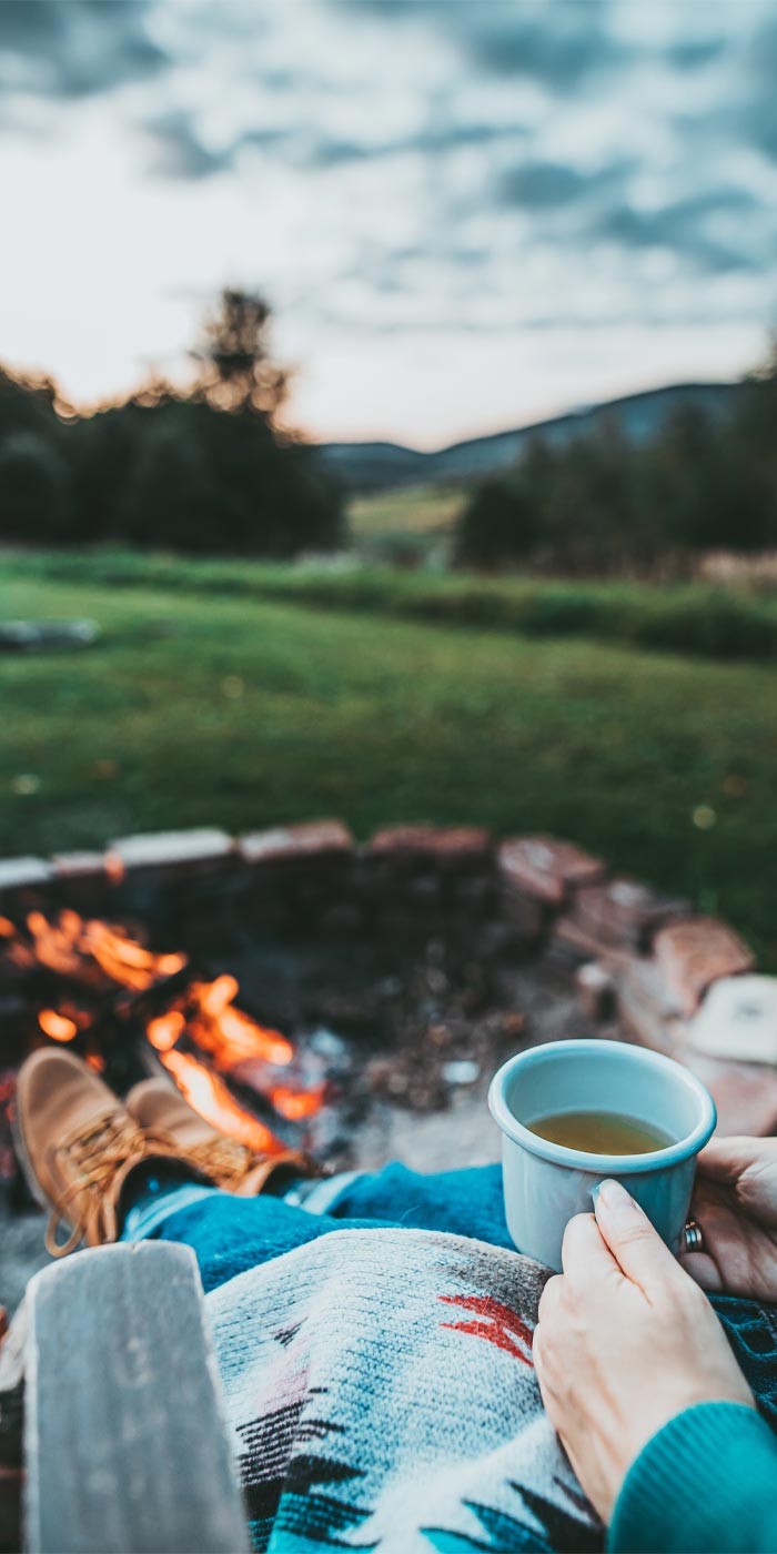 Man holding coffee cup in front of outdoor fire